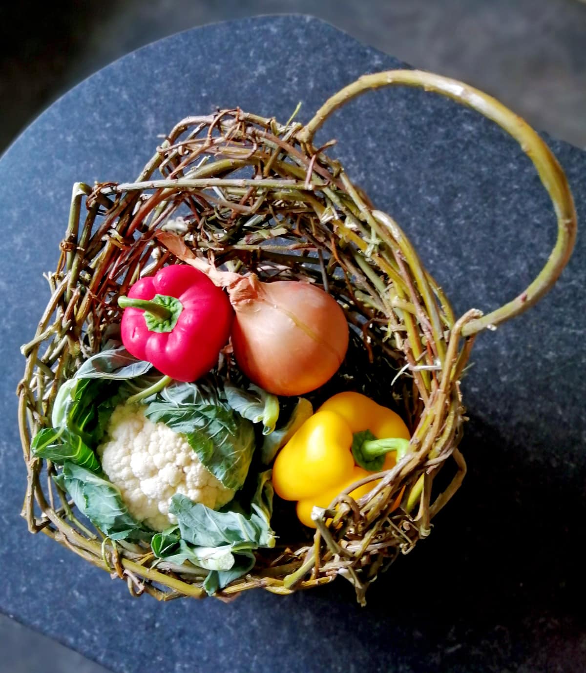 Photo of fresh vegetables in my quirky home made woven willow basket on a dark kitchen worktopVeg Basket