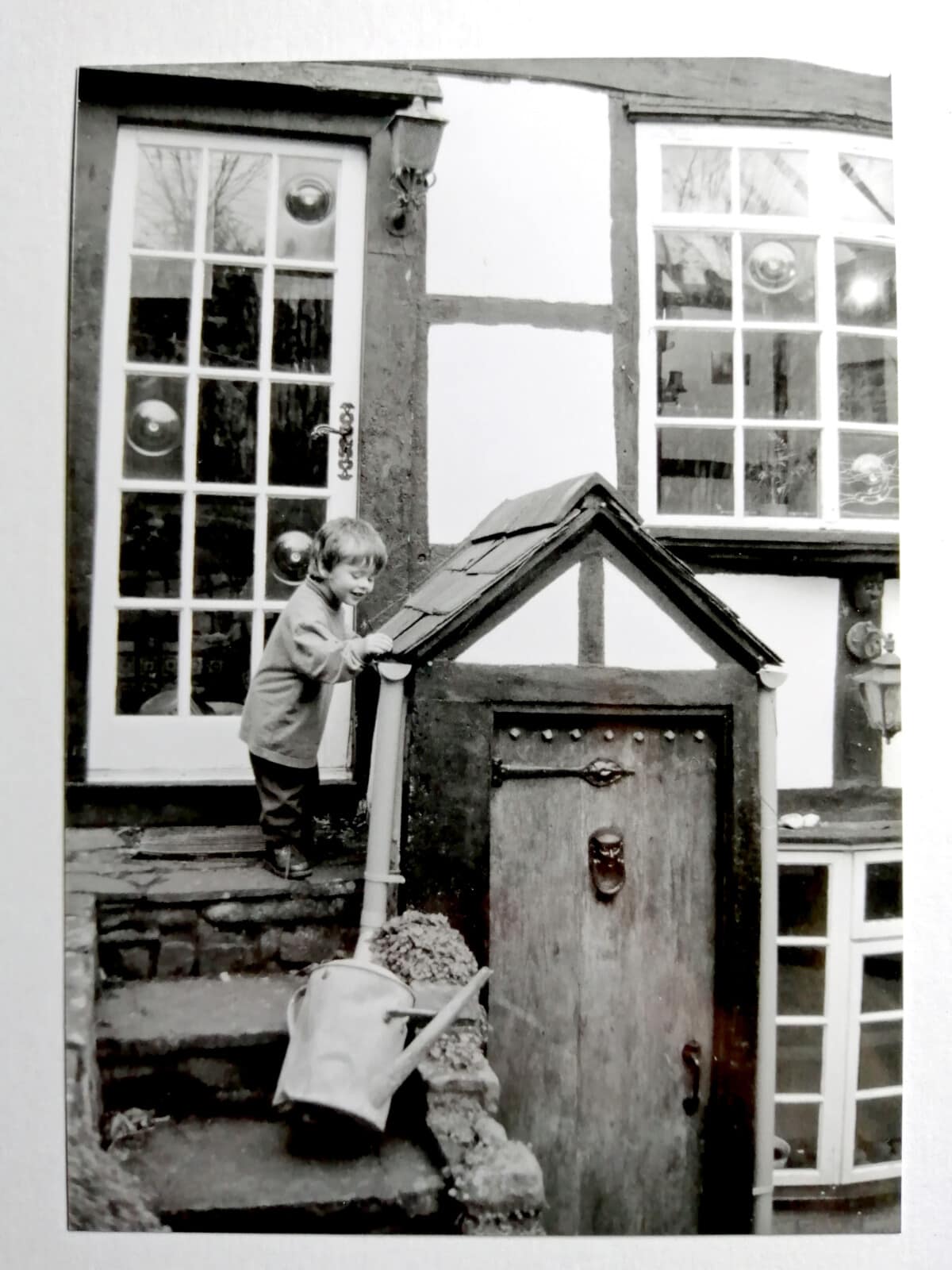 Wee boy playing in gutter of old balck and white house, Kington Herefordshire