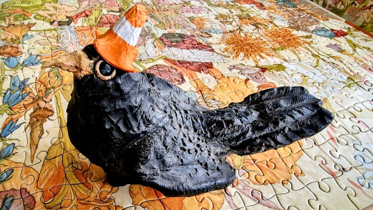 Photo of ceramic Beaky Blackbird with egg carton cone hat on a colourful jigsaw